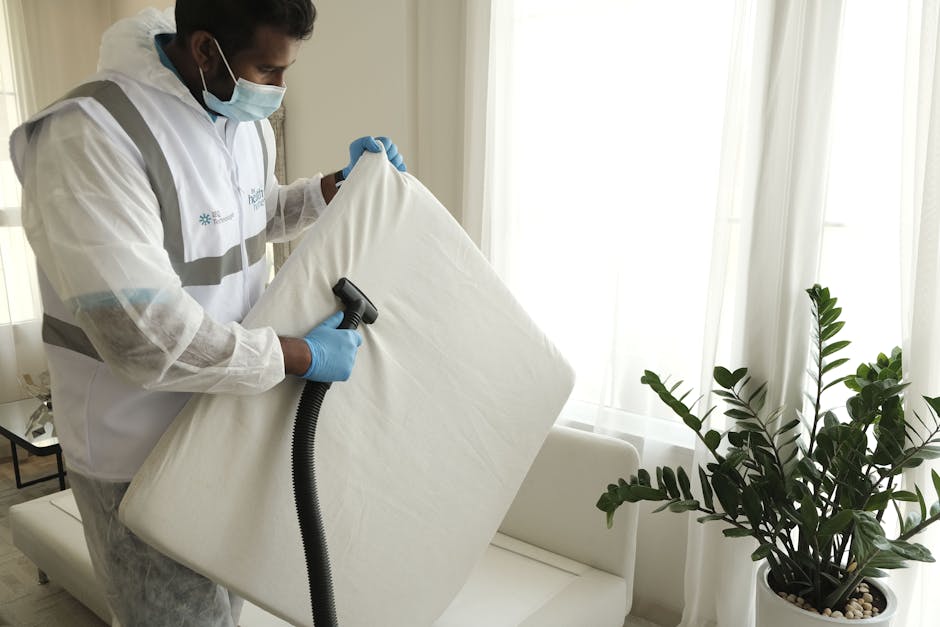 A person wearing brown gloves is placing or adjusting a rectangular illuminated sign with the words 'CLEANING HOME' in bold black letters on a wooden table within a modern, well-lit living room. The r